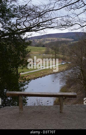 Panca in legno e si affaccia sul fiume Wharfe & Car Park a Bolton Abbey a Dales Modo lunga distanza sentiero Wharfedale Yorkshire Foto Stock