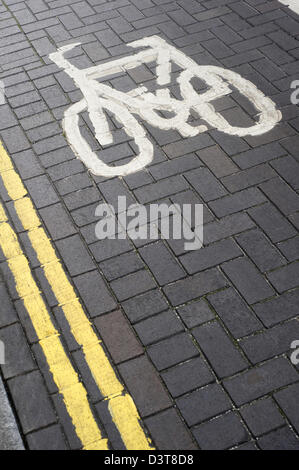 Ciclo designato Lane simbolo e doppie linee gialla della segnaletica stradale, dipinta su un mattone strada asfaltata Foto Stock