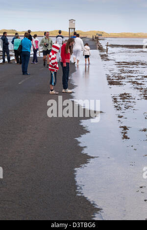 I villeggianti guarda come la marea allaga la Causeway a Isola Santa e Lindisfarne, Northumberland Inghilterra Foto Stock