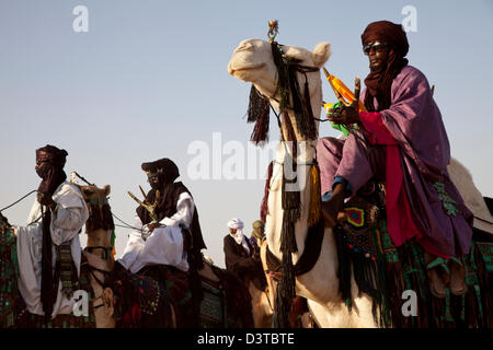 I nomadi Wodaabe cavalcare i loro cammelli come parte del Gerewol festival in Ingal, Niger Foto Stock