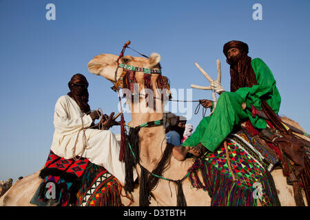 I nomadi Wodaabe cavalcare i loro cammelli come parte del Gerewol festival in Ingal, Niger Foto Stock