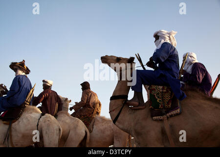 I nomadi Wodaabe cavalcare i loro cammelli come parte del Gerewol festival in Ingal, Niger Foto Stock