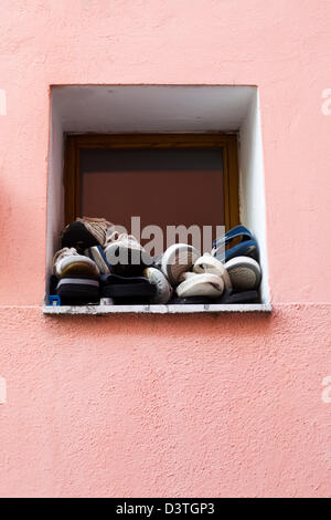 La terracotta parete dipinta con finestra piena di scarpe Foto Stock