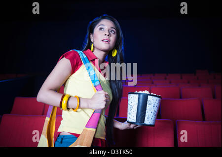 Donna godendo di filmato con popcorn in una sala cinematografica Foto Stock