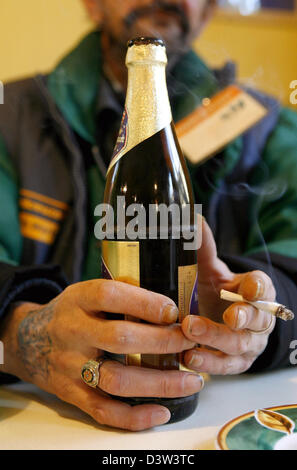 Il venditore di un senzatetto giornale" contiene una bottiglia di birra nella mano destra e una sigaretta nella mano sinistra in Nuremberg, Germania, giovedì, 14 dicembre 2006. Foto: Daniel Karmann Foto Stock