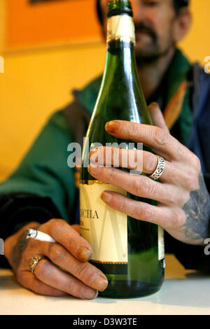 Il venditore di un senzatetto giornale" contiene una bottiglia di vino bianco nella mano sinistra e una sigaretta nella sua mano destra in Nuremberg, Germania, giovedì, 14 dicembre 2006. Foto: Daniel Karmann Foto Stock