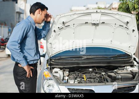 Imprenditore bengalesi in piedi vicino a ripartiti in auto Foto Stock