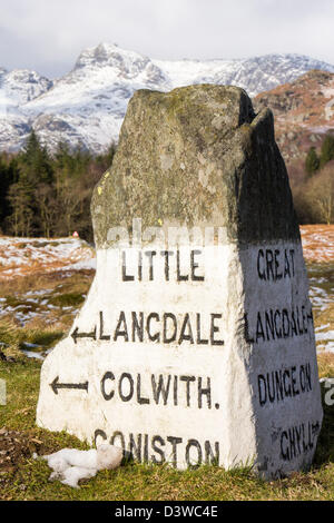 Un vecchio cartello stradale su Elterwater comune in The Langdale valley, guardando verso il Langdale pikes, Lake District, Regno Unito, Foto Stock