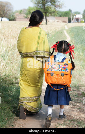 Donna che cammina con il suo schoolgirl nel campo, Sohna, Haryana, India Foto Stock