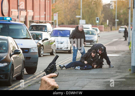 La polizia di affrontare un negozio lifter a Manchester e combattiamo lui a terra e una pistola a mano. Foto Stock