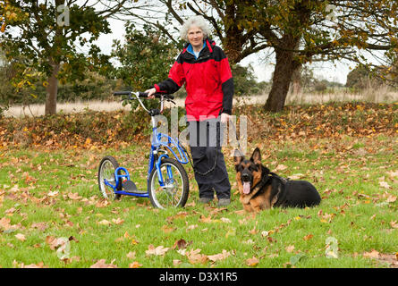 Una donna in piedi accanto al suo scooter che è un design speciale per essere trainato da un cane Foto Stock