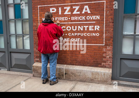 Uomo di verniciatura di un segno di una pizzeria con un po' di Italia nella città di New York Foto Stock