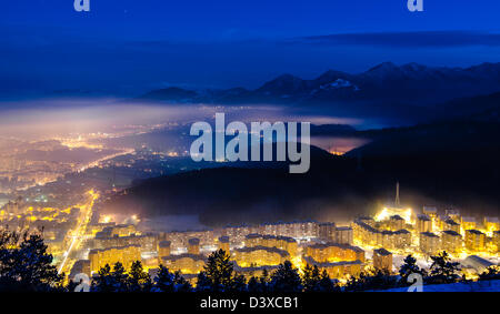 Una notte di esposizione al di sopra della città di Brasov con Piatra Mare montagne sullo sfondo Foto Stock