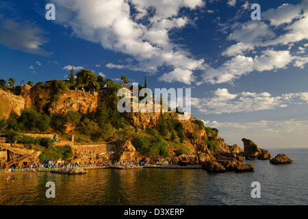 Cliffside resort e la spiaggia sulla Riviera turca a Antalya Kaleici Harbour la Turchia al tramonto Foto Stock