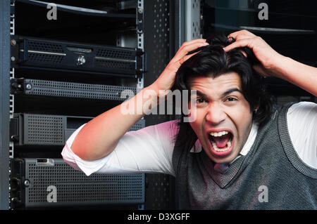 Frustrati networking engineer tirando i capelli in una sala server Foto Stock