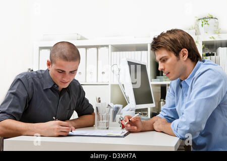 Un tardo 20's manager personale dà il contratto di lavoro per un personale di nuova assunzione che poi le indicazioni. Foto Stock