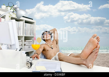 Giovane uomo al lavoro fantasticando su beach, cocktail e vita facile Foto Stock