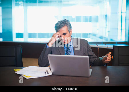 Preoccupato per il businessman seduta con il computer portatile Foto Stock