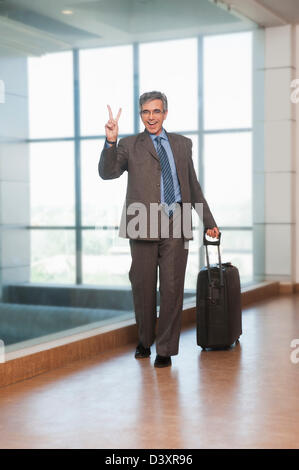 Ritratto di un imprenditore che mostra un segno di pace e sorridente Foto Stock