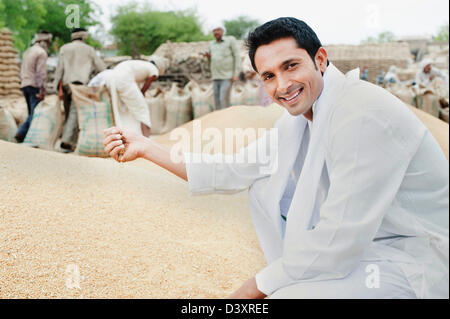 Man Picking chicchi di grano da un heap, Anaj Mandi, Sohna, Gurgaon, Haryana, India Foto Stock