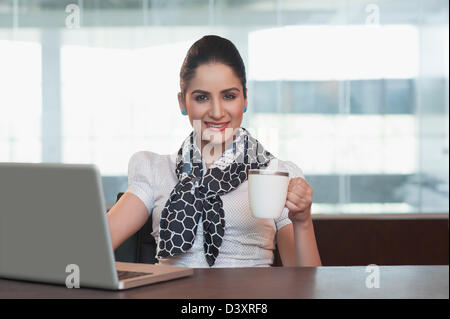 Imprenditrice di bere il caffè e sorridente Foto Stock