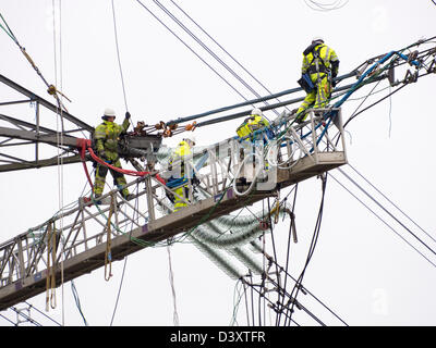 I tecnici al lavoro per sostituire i vecchi isolatori su un pilone in Barrow su Soar, Leicestershire, Regno Unito. Foto Stock