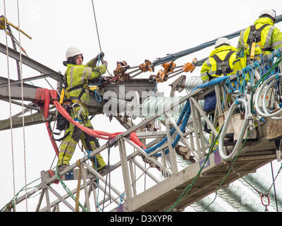 I tecnici al lavoro per sostituire i vecchi isolatori su un pilone in Barrow su Soar, Leicestershire, Regno Unito. Foto Stock