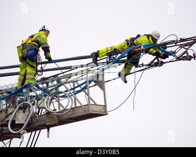 I tecnici al lavoro per sostituire i vecchi isolatori su un pilone in Barrow su Soar, Leicestershire, Regno Unito. Foto Stock