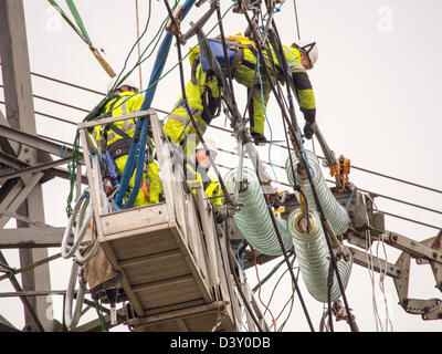 I tecnici al lavoro per sostituire i vecchi isolatori su un pilone in Barrow su Soar, Leicestershire, Regno Unito. Foto Stock