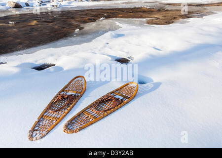 In legno classico zampa orso racchette da neve sulla riva del parzialmente congelato di Cache la Poudre River vicino a Fort Collins, Colorado Foto Stock