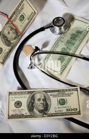 Ancora la vita di centinaia di fatture del dollaro e stetoscopio medico sul bianco del camice, STATI UNITI D'AMERICA Foto Stock