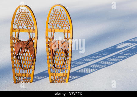 Una coppia di classico Bear Paw di racchette da neve in legno gettato ombra nella neve Foto Stock