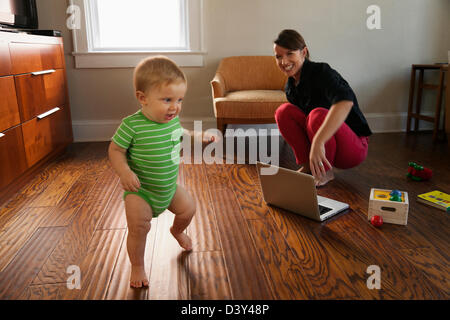 Madre caucasica guardando toddler figlio a piedi Foto Stock