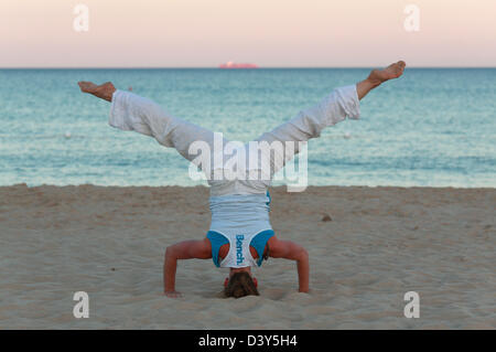 Santa Margherita di Pula, Italia, donna facendo un headstand sulla spiaggia Foto Stock