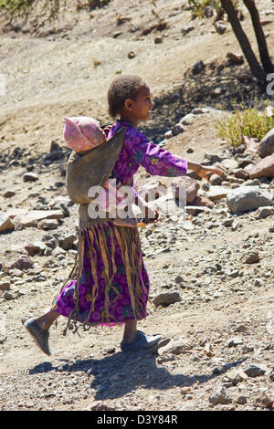 Ragazza locale con il bambino sul ciglio della strada in nord Africa Etiopia Foto Stock