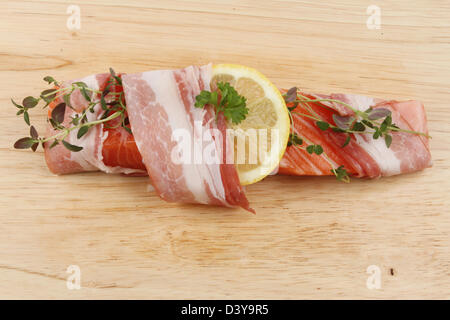 Bistecca di salmone avvolto in pancetta con limone e timo su una tavola di legno Foto Stock