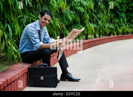 Imprenditore leggendo un giornale in un parco Foto Stock