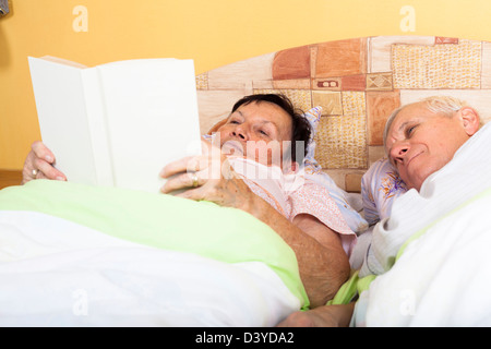 Close up di felice coppia senior libro di lettura a letto. Foto Stock