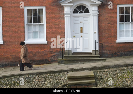 Donna in pelliccia e hat passeggiate passato Georgian House no.38 in Broad Street, Ludlow, Shropshire, Inghilterra, Gran Bretagna Foto Stock