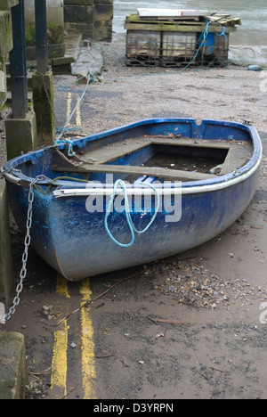 Piccola barca a terra collegato da una catena, parcheggiato di fronte a doppia linea gialla della segnaletica stradale, east twickenham, middlesex, Inghilterra Foto Stock