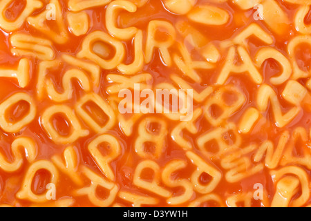 Sfondo di pasta a forma di lettere dell'alfabeto in una salsa di pomodoro Foto Stock