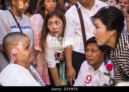 Bangkok, Tailandia. Il 27 febbraio 2013. Pol Gen PONGSAPAT PONGCHAREON (centro) e YINGLUCK Shinawatra, primo ministro della Thailandia, (destra) parlare con una donna gravemente ustionata durante la loro campagna per Pongsapat elezioni a governatore di Bangkok. Polizia Pongsapat generale Pongcharoen (pensionati), un ex vice nazionale capo di polizia che ha anche servito come segretario generale del controllo degli stupefacenti è il Pheu Thai candidato del partito nel prossimo governatore di Bangkok di elezione. (Si dimise dalla forza di polizia a correre per la carica di governatore.) Credito: ZUMA Press, Inc. / Alamy Live News Foto Stock