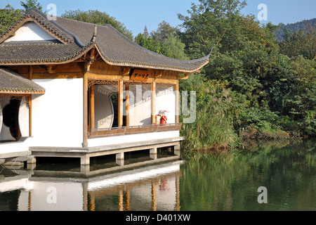 Giovane vestito in cinese tradizionale costume in posa di un Padiglione sul Lago di Hangzhou - Hangzhou vicino a Shanghai in Cina Foto Stock