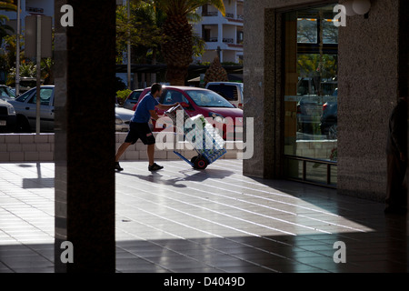 Soft drink uomo consegna spingendo un sacco carrello con le lattine e bottiglie di un centro commerciale di Los Cristianos, Tenerife, Foto Stock