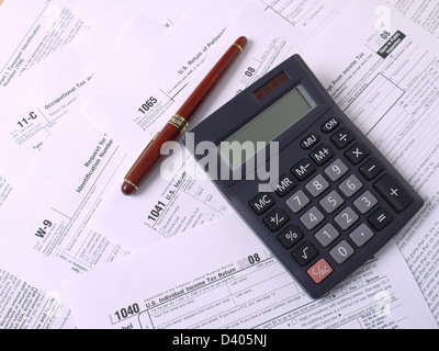 Calcolatrice e penna a inchiostro di posa su vari reddito americano moduli fiscali Foto Stock