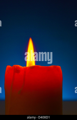 In prossimità di una candela che brucia contro sfondo blu Foto Stock