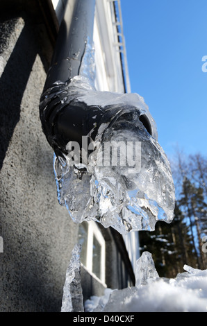 Close-up di congelati drainpipe, parete e cielo blu Foto Stock