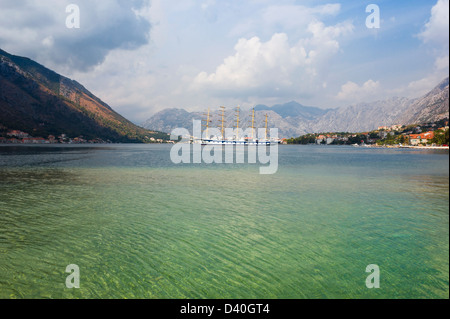 Nave a vela nelle calme acque della Baia di Kotor in Montenegro in un soleggiato e luminoso giorno con cielo blu e belle nuvole bianche. Foto Stock