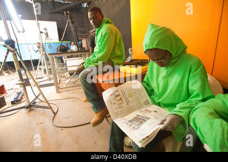 Nairobi, in Kenya. 26 feb 2013. Burattinaio in greenscreen outfit prendendo una pausa e la lettura di un quotidiano tra le scene riprese mentre l elezione puntata speciale del keniota satira politica "XYZ Show'. Lo spettacolo presenta una parodia del telegiornale di lattice burattini. Foto Stock