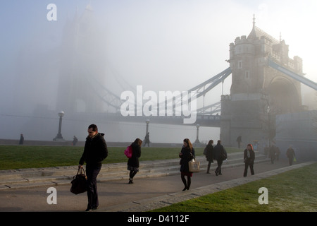 Un'immagine mostra i pendolari a piedi dal Tower Bridge attraverso la fitta nebbia e basse nubi a Londra. Foto Stock